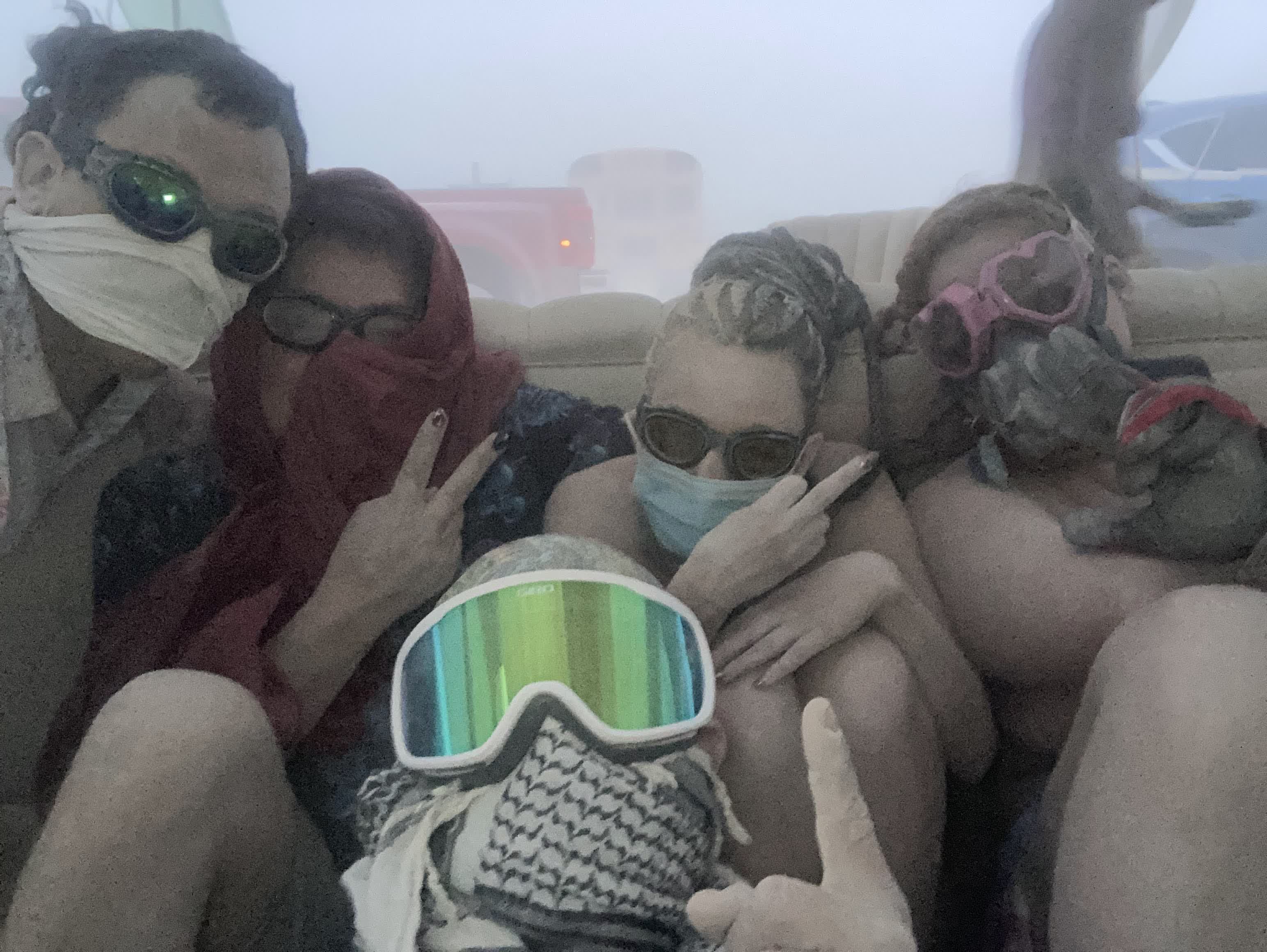 Campers huddled on a couch in goggles and masks during a dust storm