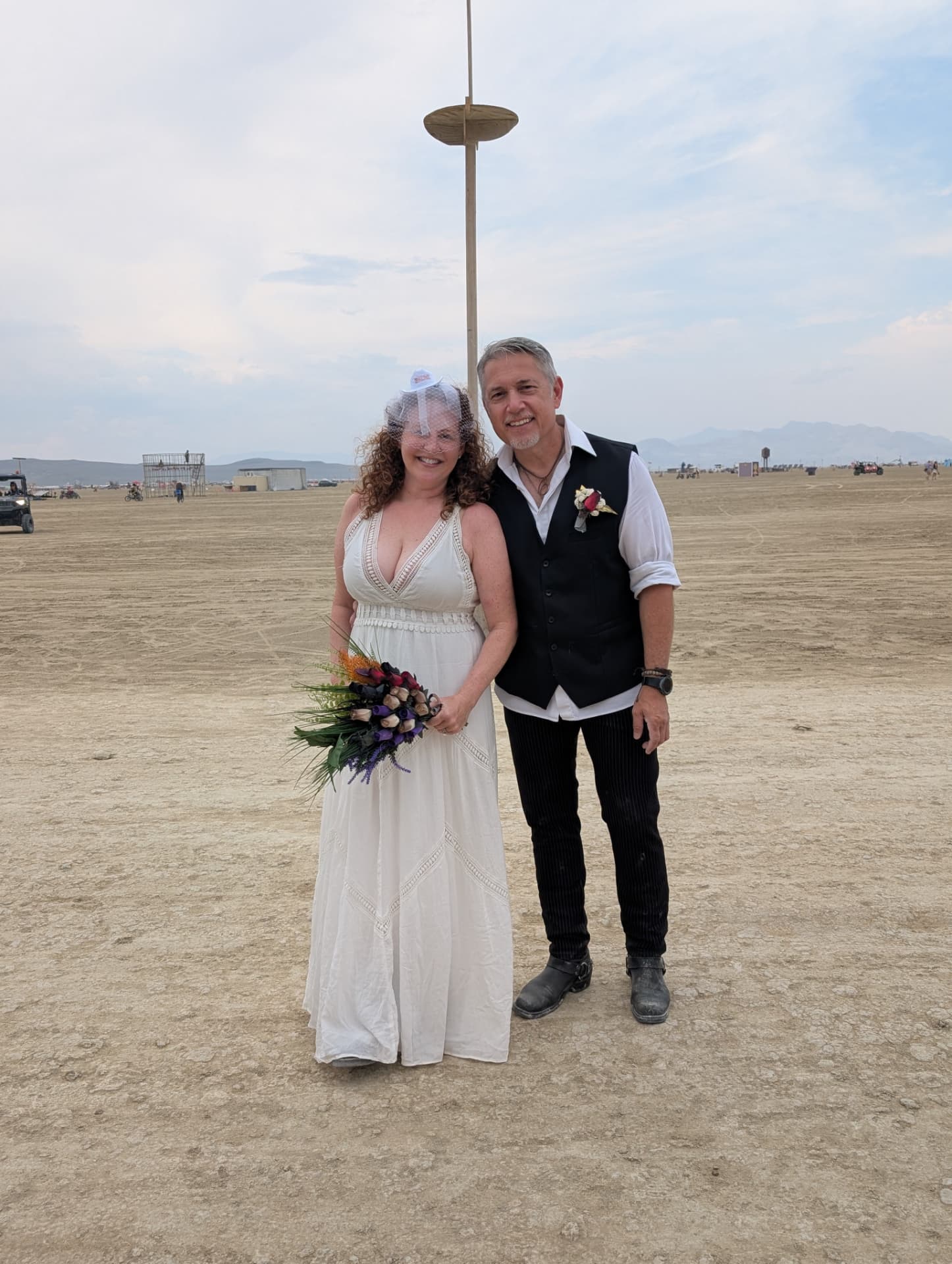 The married couple standing together on the open playa