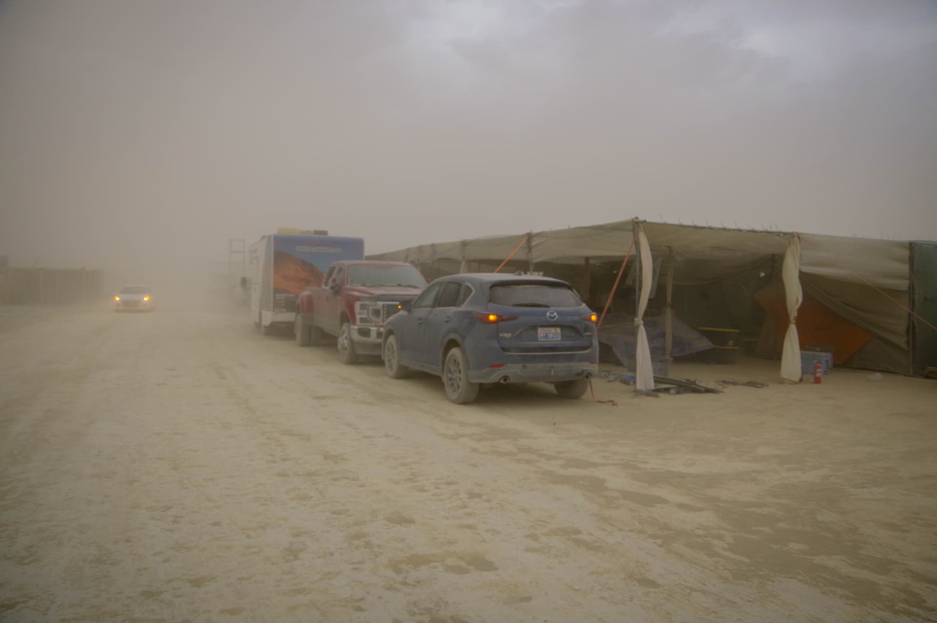 Vehicles and camp structures barely visible through a thick dust storm